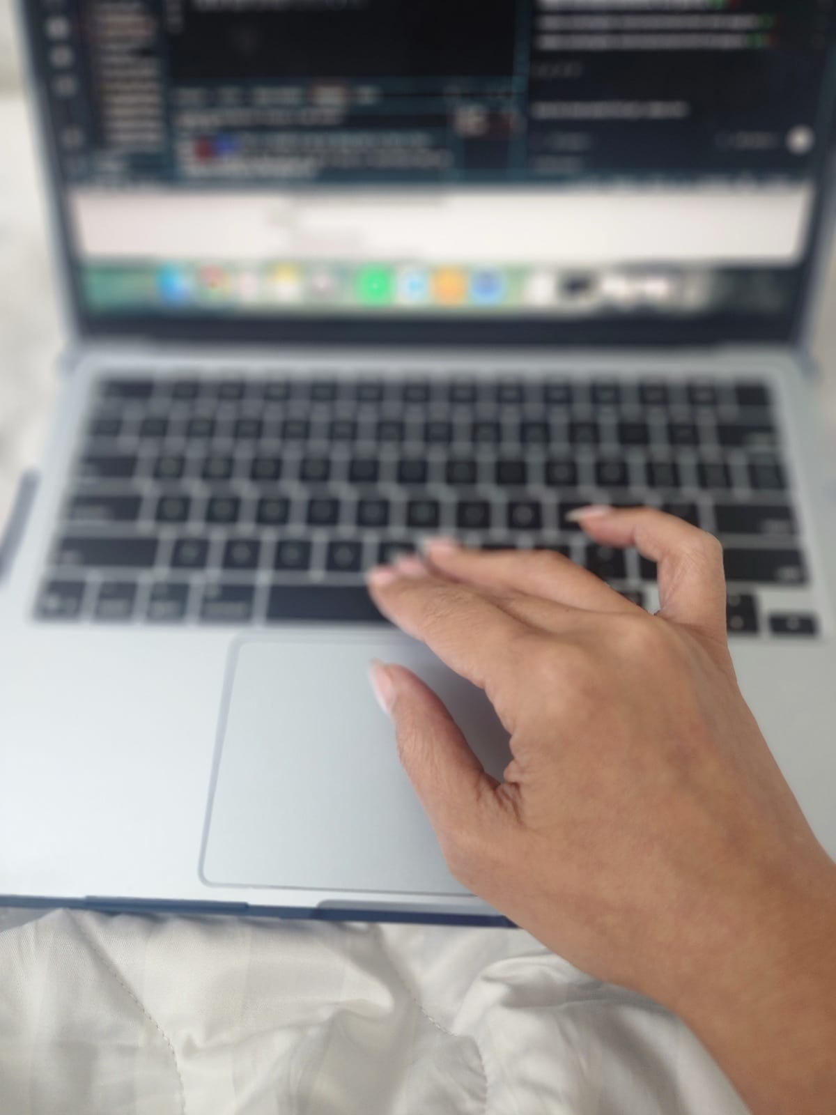 Close-up of a hand using a laptop with code on screen.